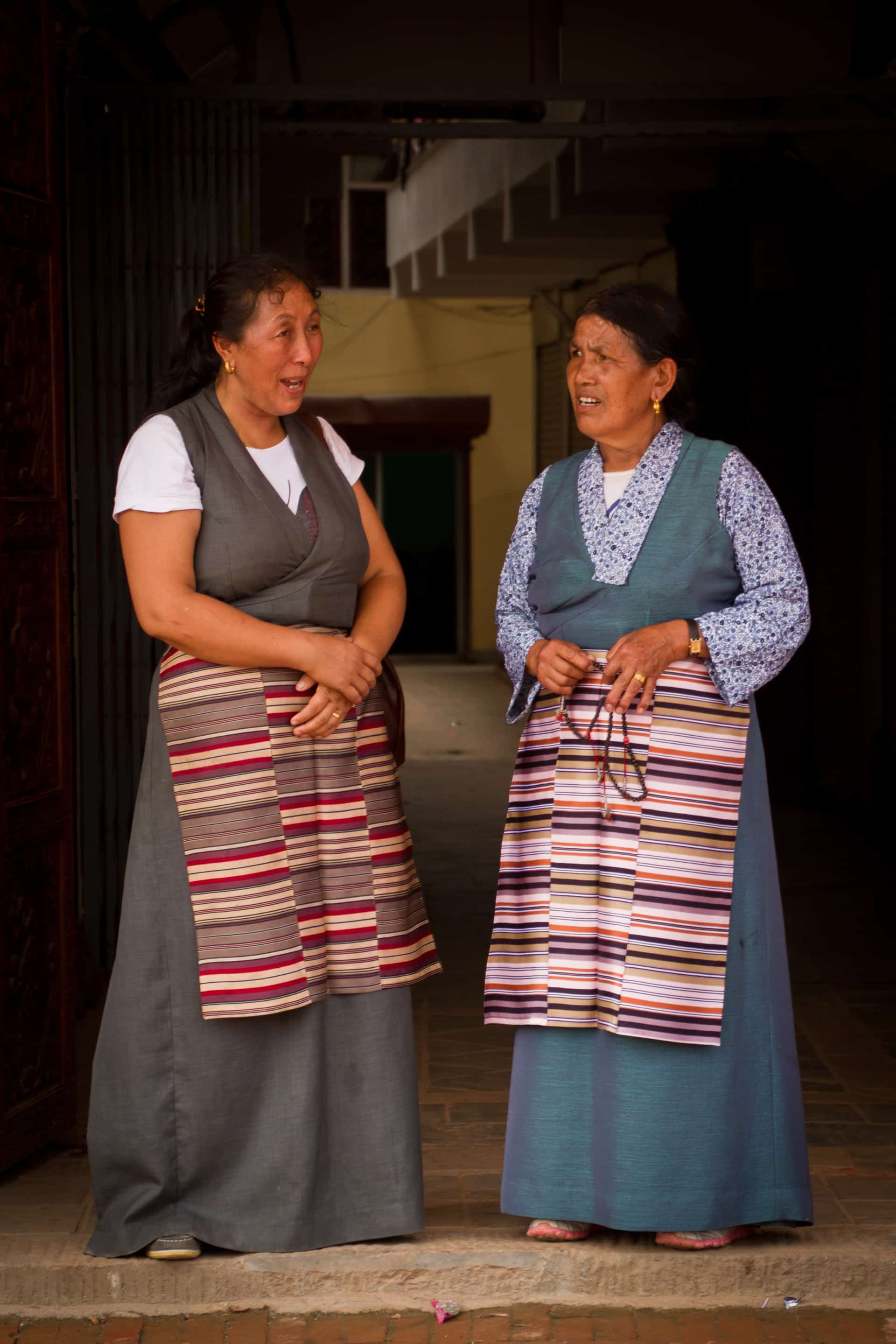 Two Tibetan Buddhist ladies in traditional dress talk together in Boudhanath Temple, Kathmandu, Nepal